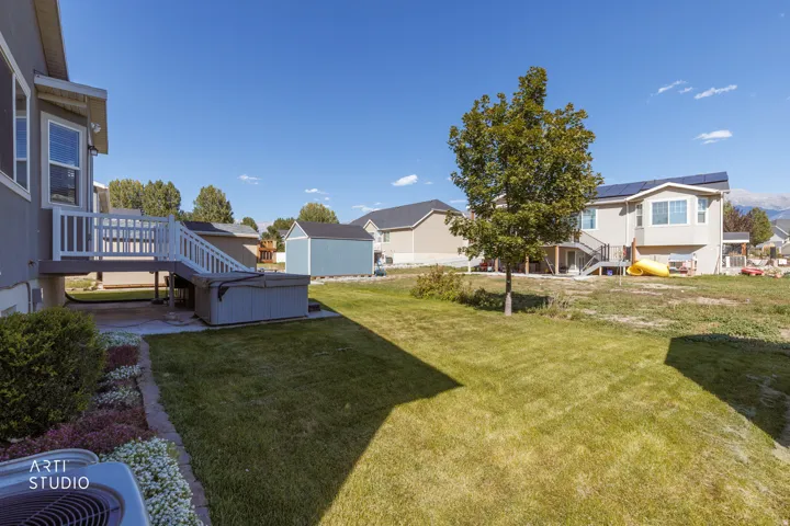 Expansive backyard featuring a manicured lawn, built-in hot tub, and a raised deck with white railings