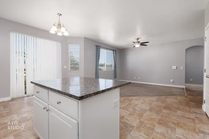 Kitchen island with granite-style countertop, white cabinetry, and brushed nickel hardware