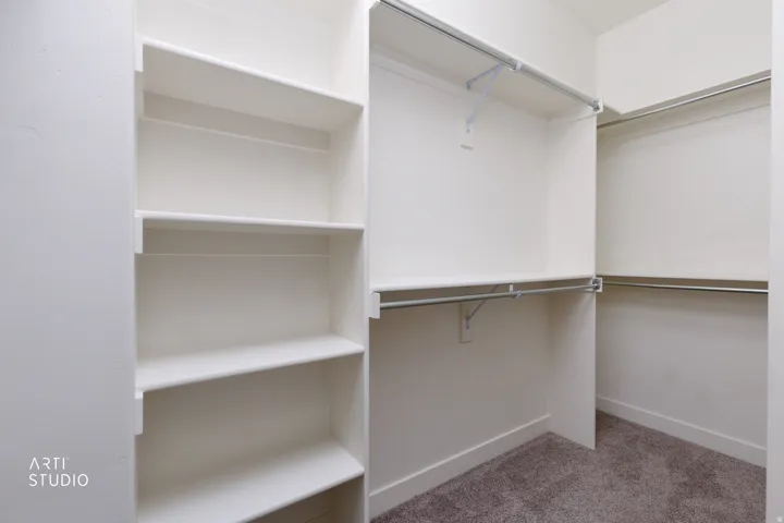 Built-in white shelving, multiple hanging rods, and dark gray carpet
