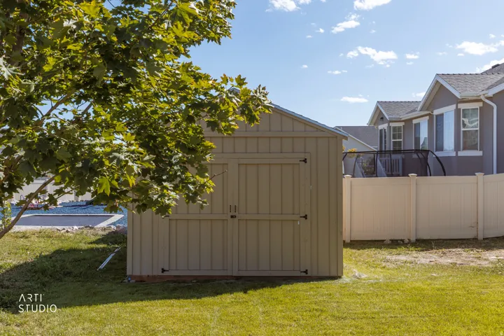 Expansive backyard featuring a manicured lawn, an outdoor storage shed, and a privacy fence