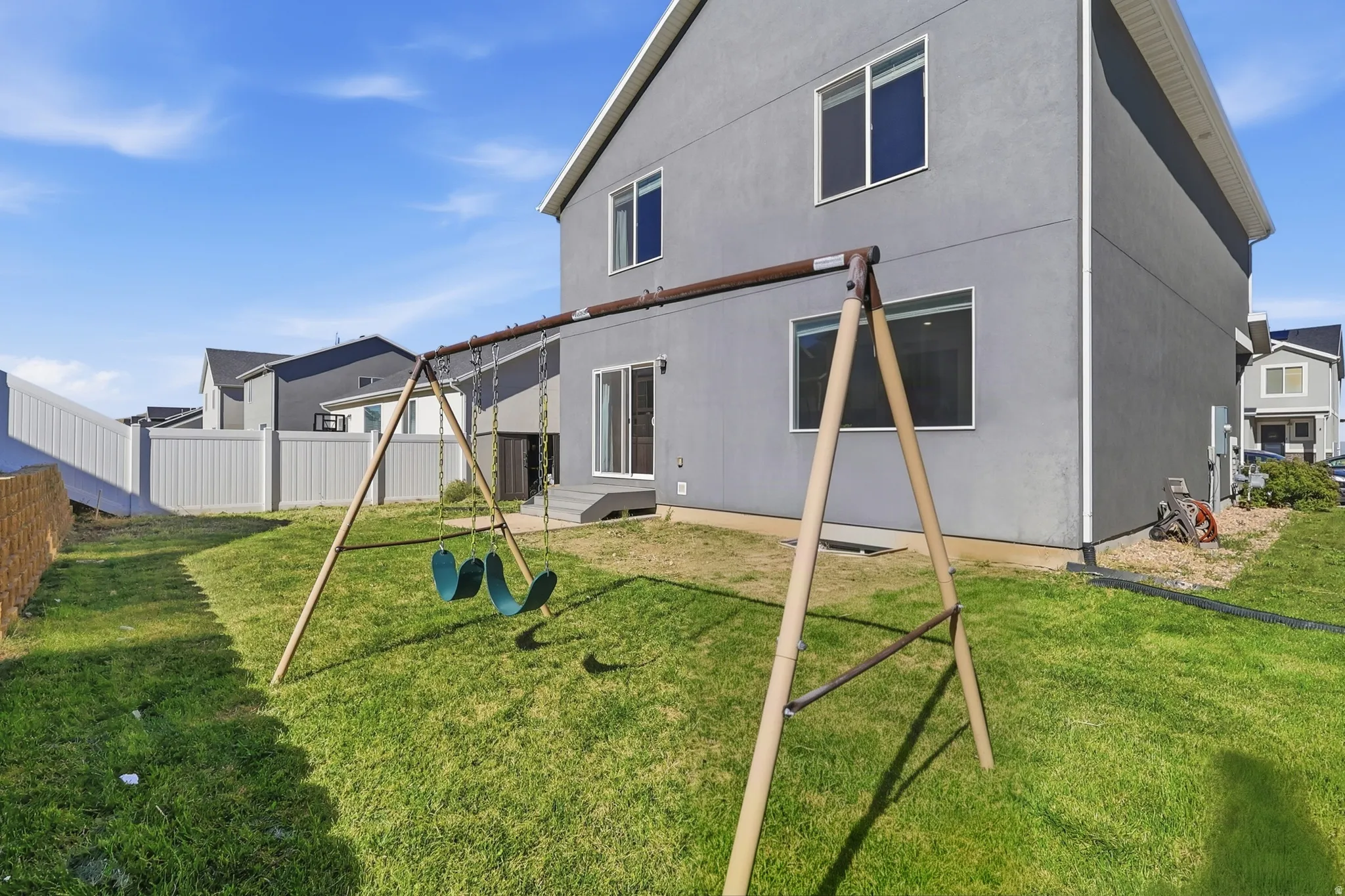 Expansive grassy yard area with a white privacy fence and a rear deck with sliding glass door access