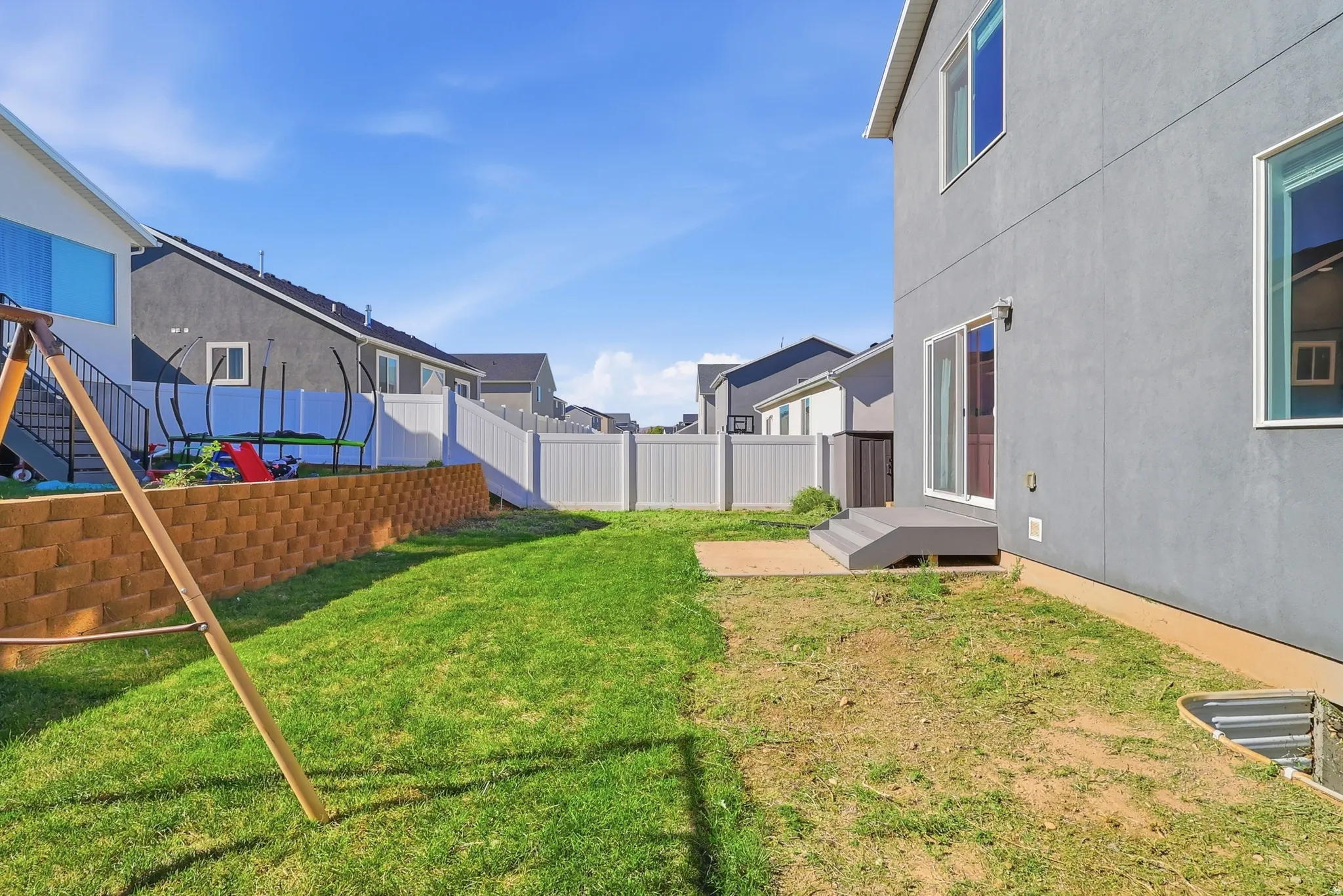 Fenced backyard featuring a retaining wall, a concrete patio, and a sliding glass door