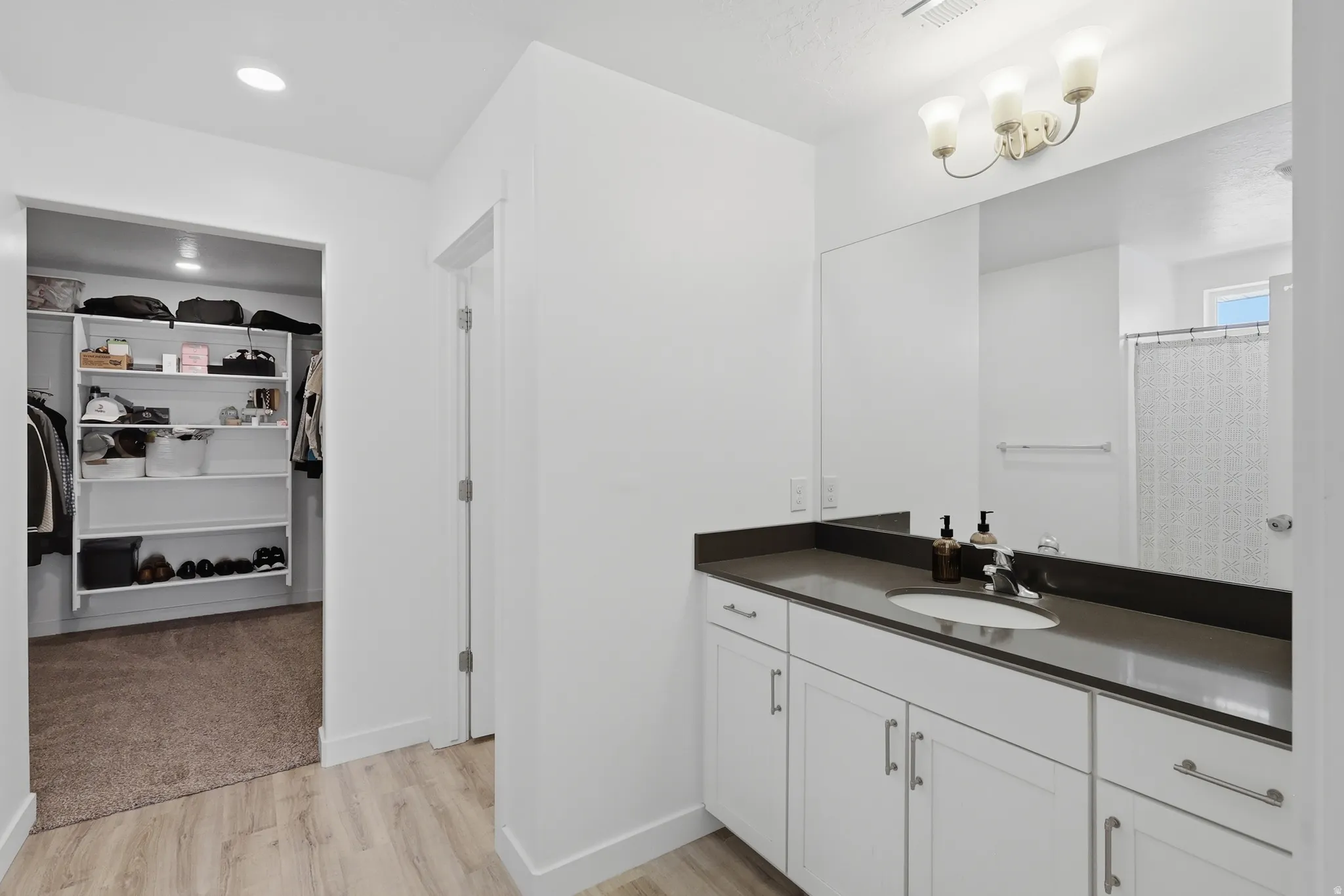 White vanity with built-in sink, dark countertop, and large mirror