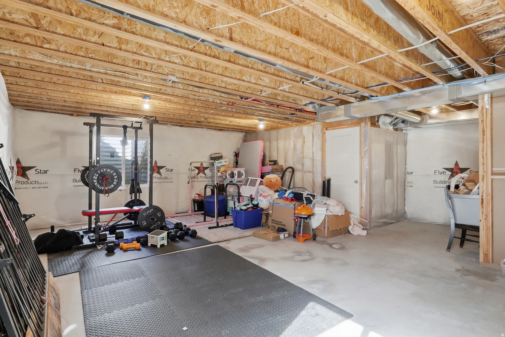 Unfinished basement featuring exposed wood joists, concrete flooring, and a window providing natural light