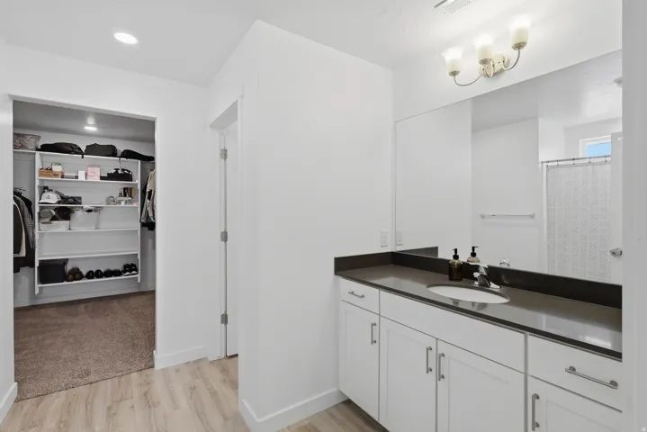 White vanity with built-in sink, dark countertop, and large mirror