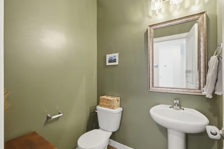 Pedestal sink with a polished chrome faucet, framed mirror, and a wall-mounted light fixture
