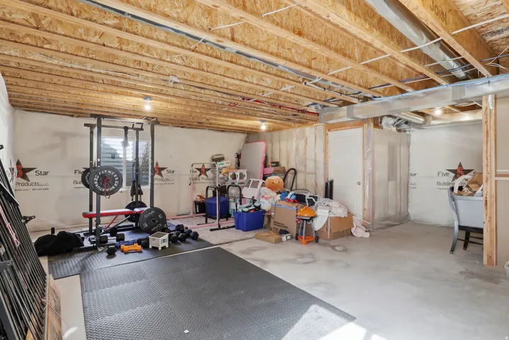 Unfinished basement featuring exposed wood joists, concrete flooring, and a window providing natural light