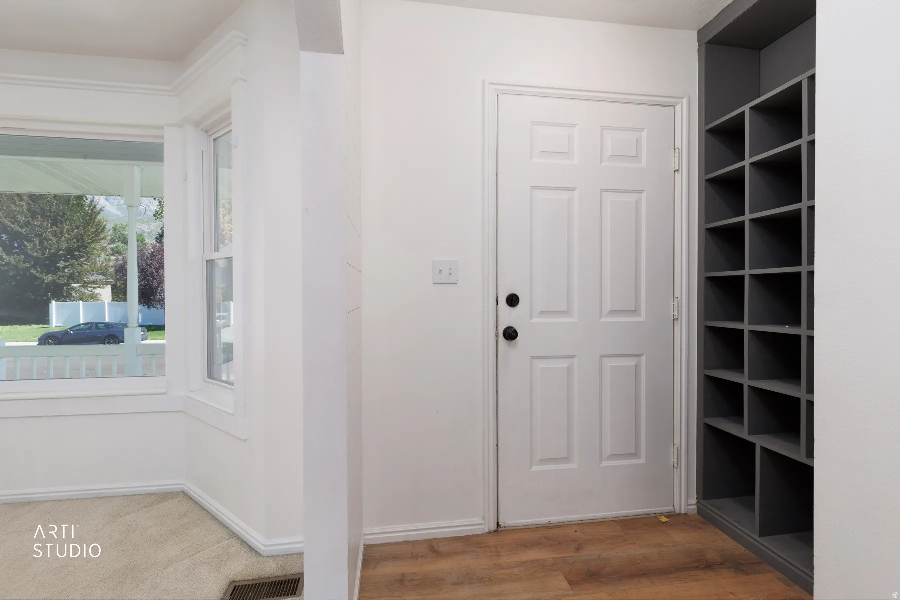 Built-in shelving unit, wood-finish flooring, paneled door with dark hardware, and double-hung windows