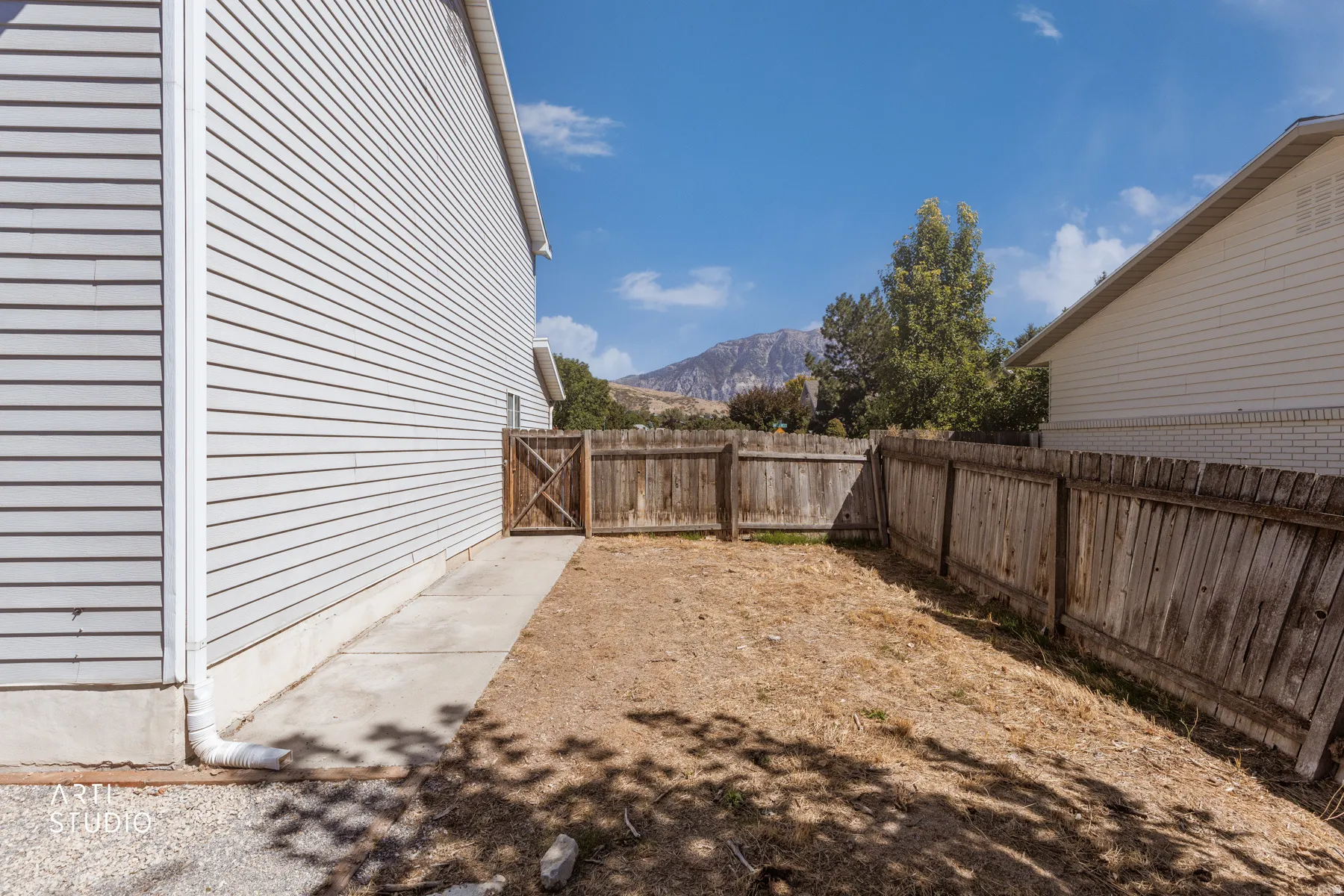Siding exterior, concrete walkway, and wooden fence with gate