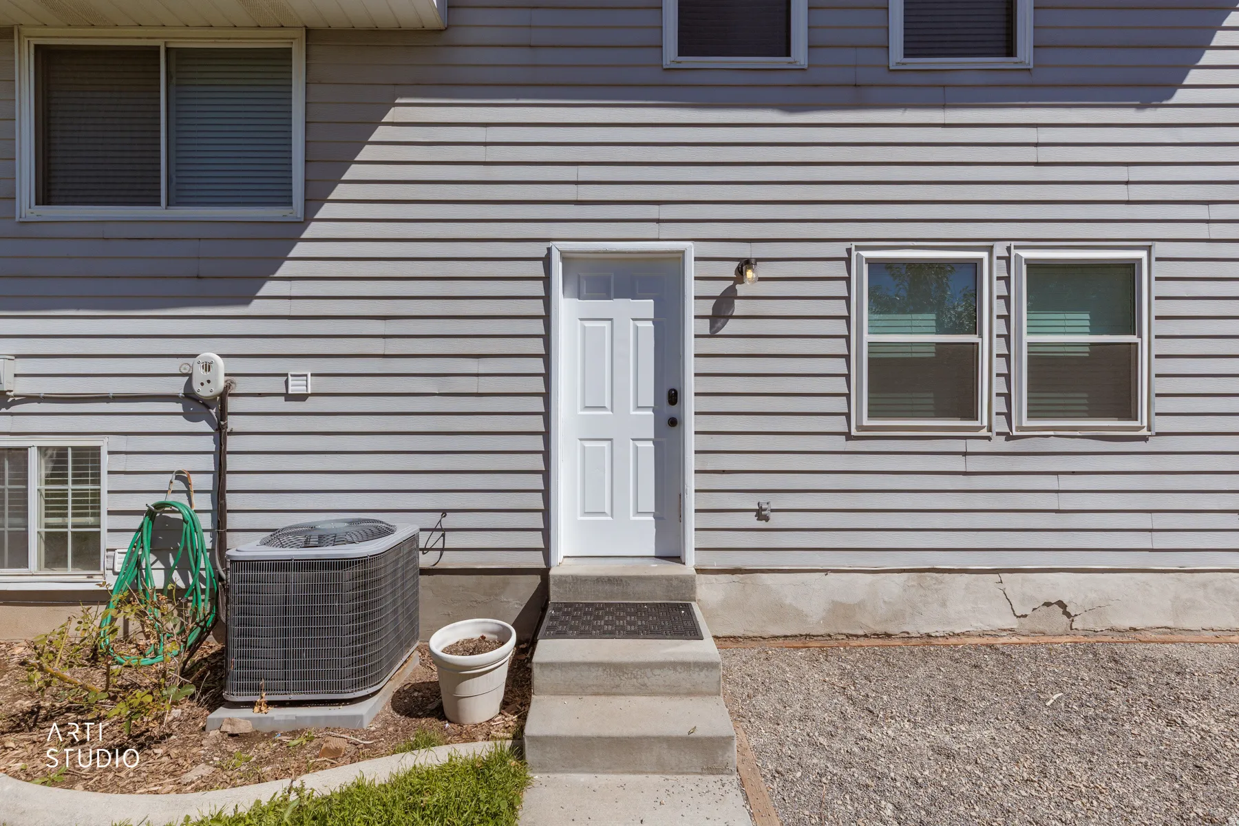 Light gray horizontal siding with a white panel door and exterior sconce lighting