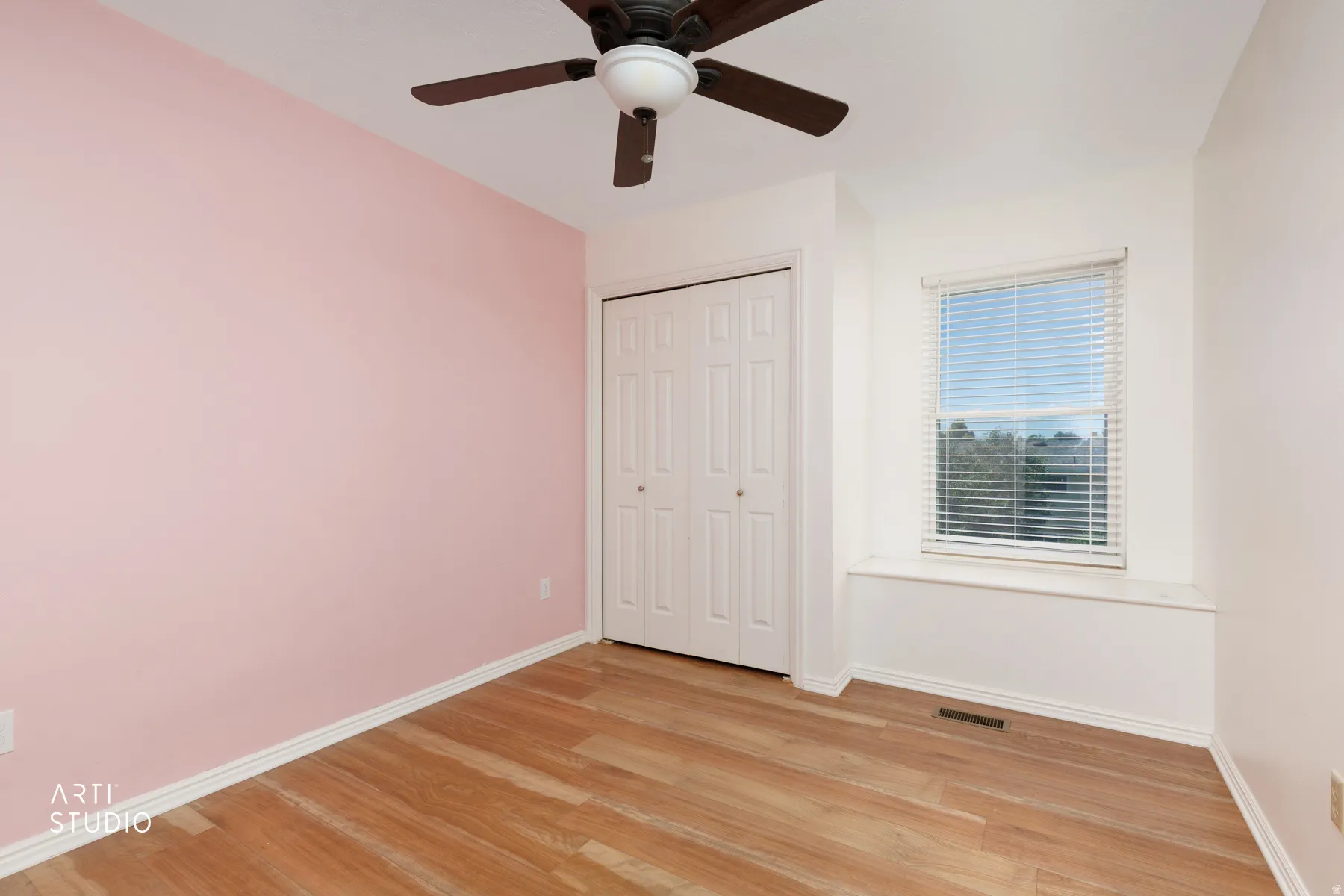 Wood-finish flooring, ceiling fan, bi-fold closet doors, and window with blinds