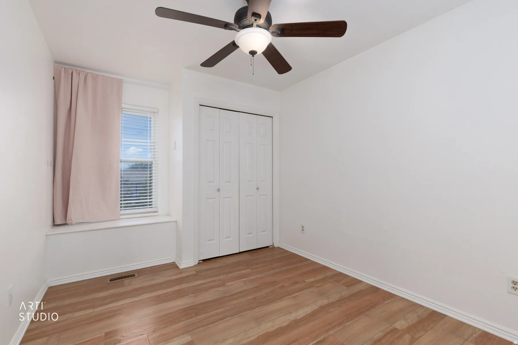 Wood-finish flooring, white walls, built-in bi-fold closet, ceiling fan with integrated lighting, and window with blinds