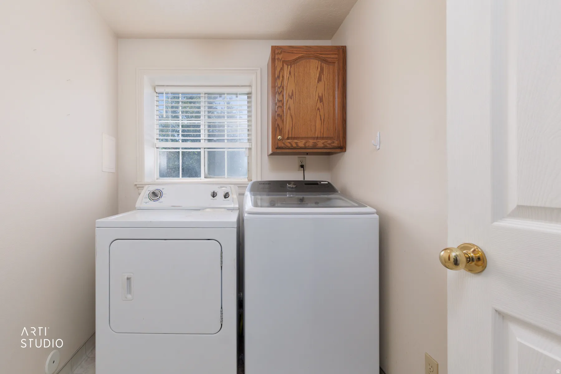 Laundry area featuring a window, wood-finish cabinetry, and neutral wall tones