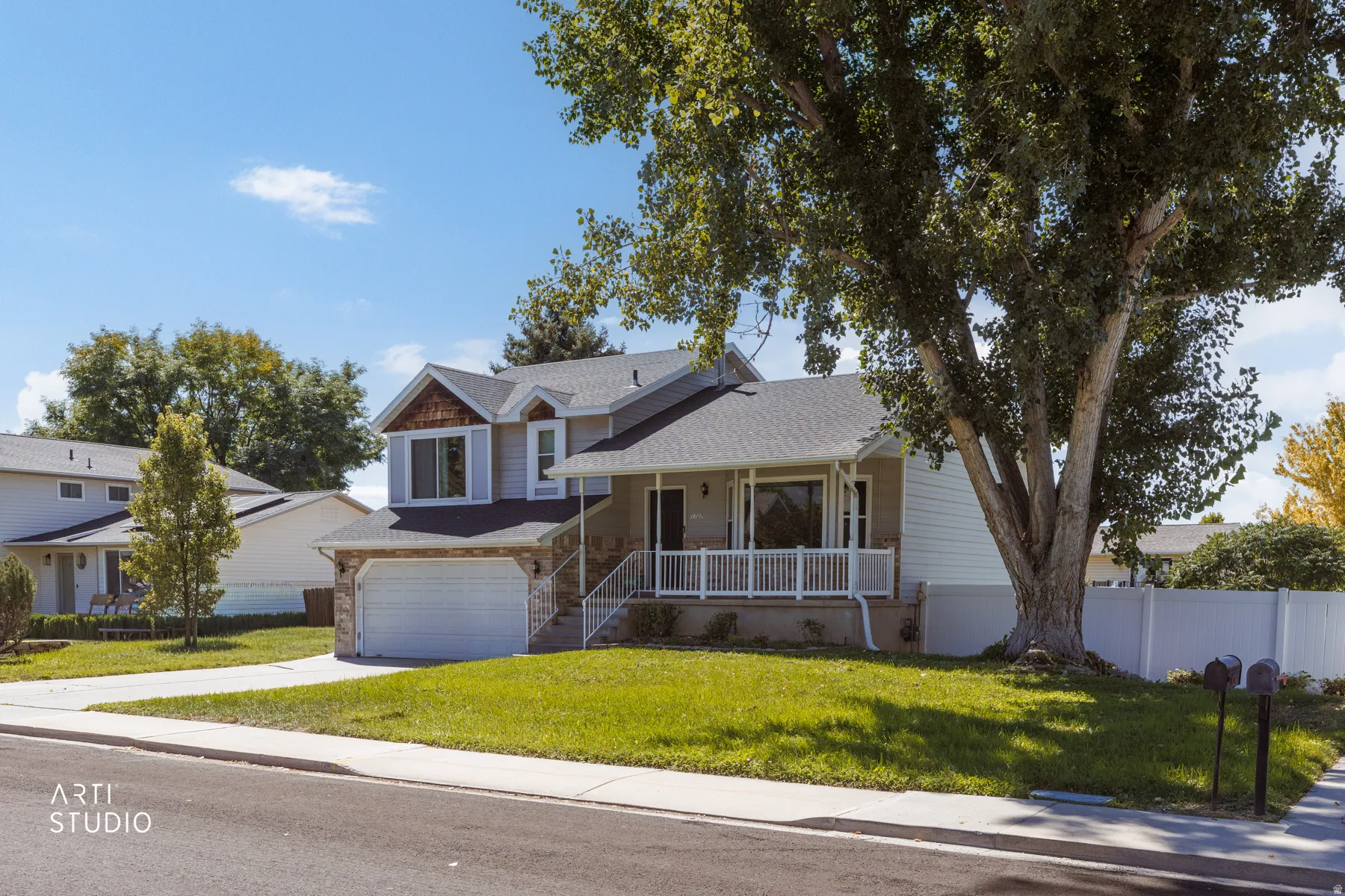 Two-story residence with a light-colored siding exterior, stone accents, and a two-car garage