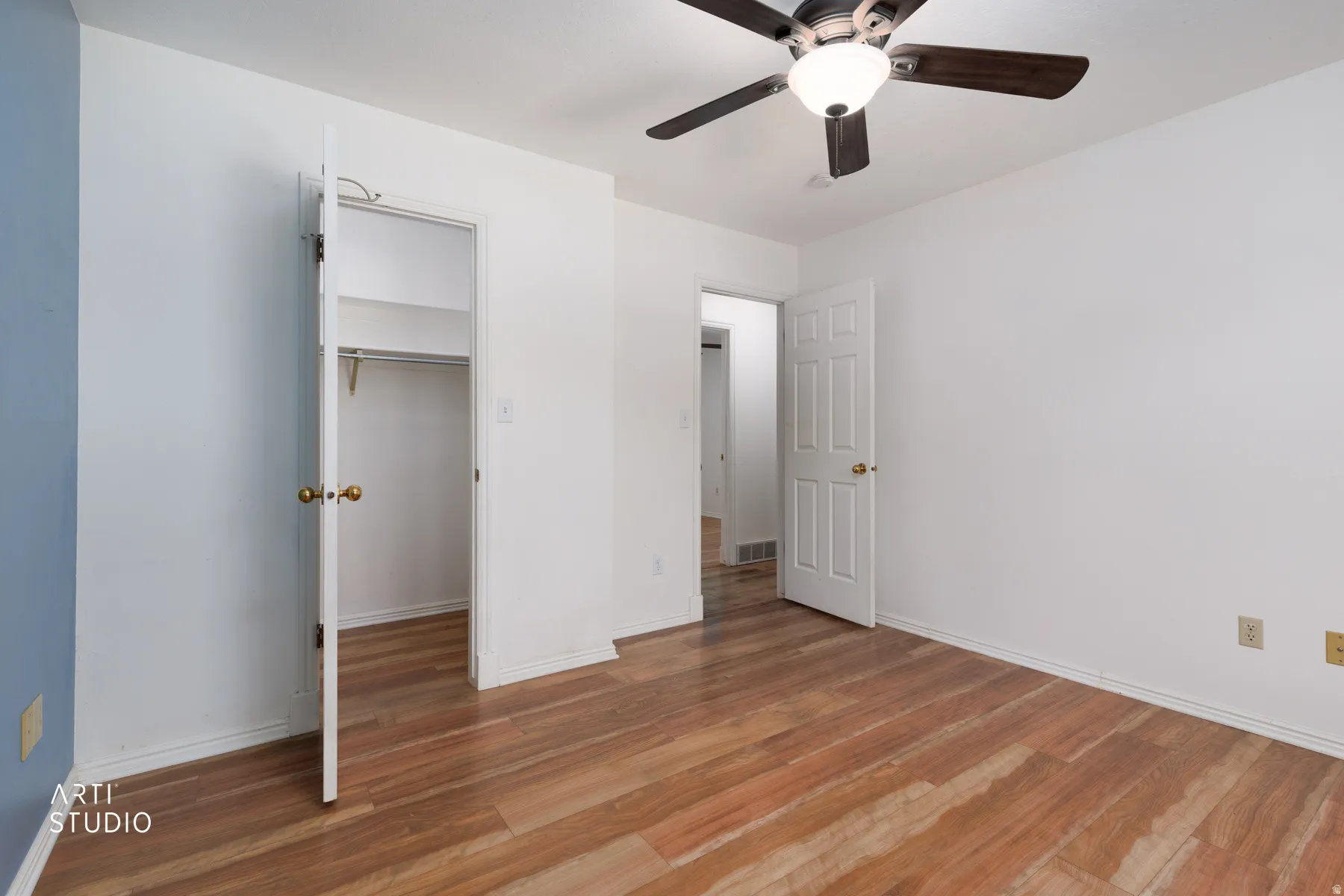 Wood-finish flooring throughout, white painted walls, and a built-in ceiling fan with integrated lighting