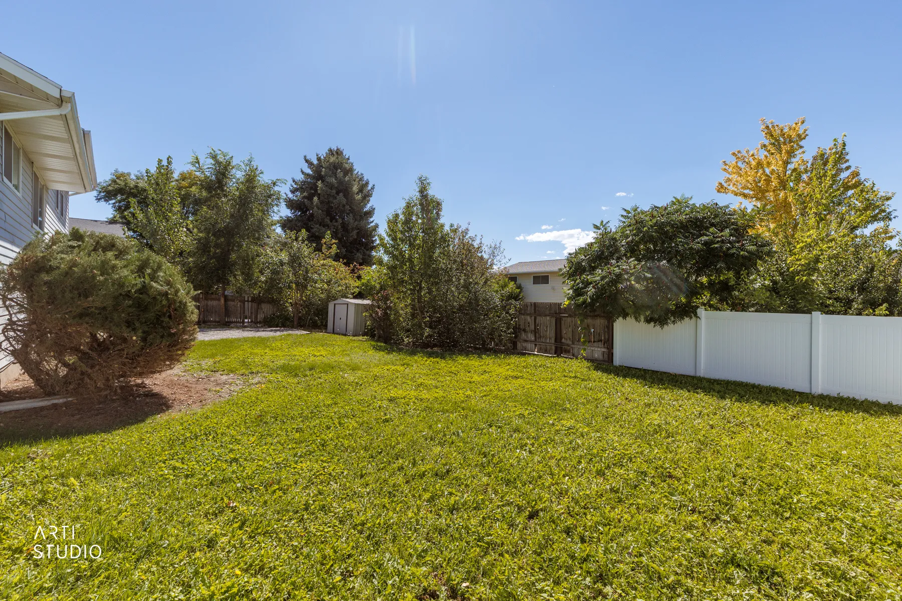 Expansive lawn area, white privacy fencing, and mature perimeter trees