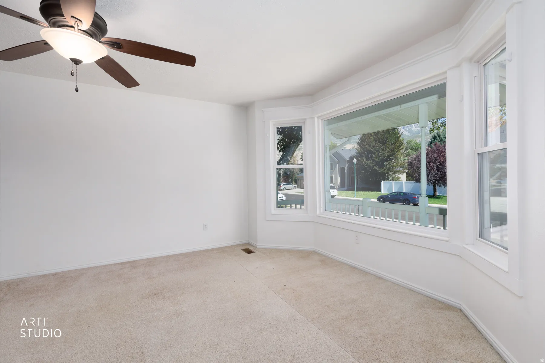 Bay window with white trim, ceiling fan, and carpeted flooring