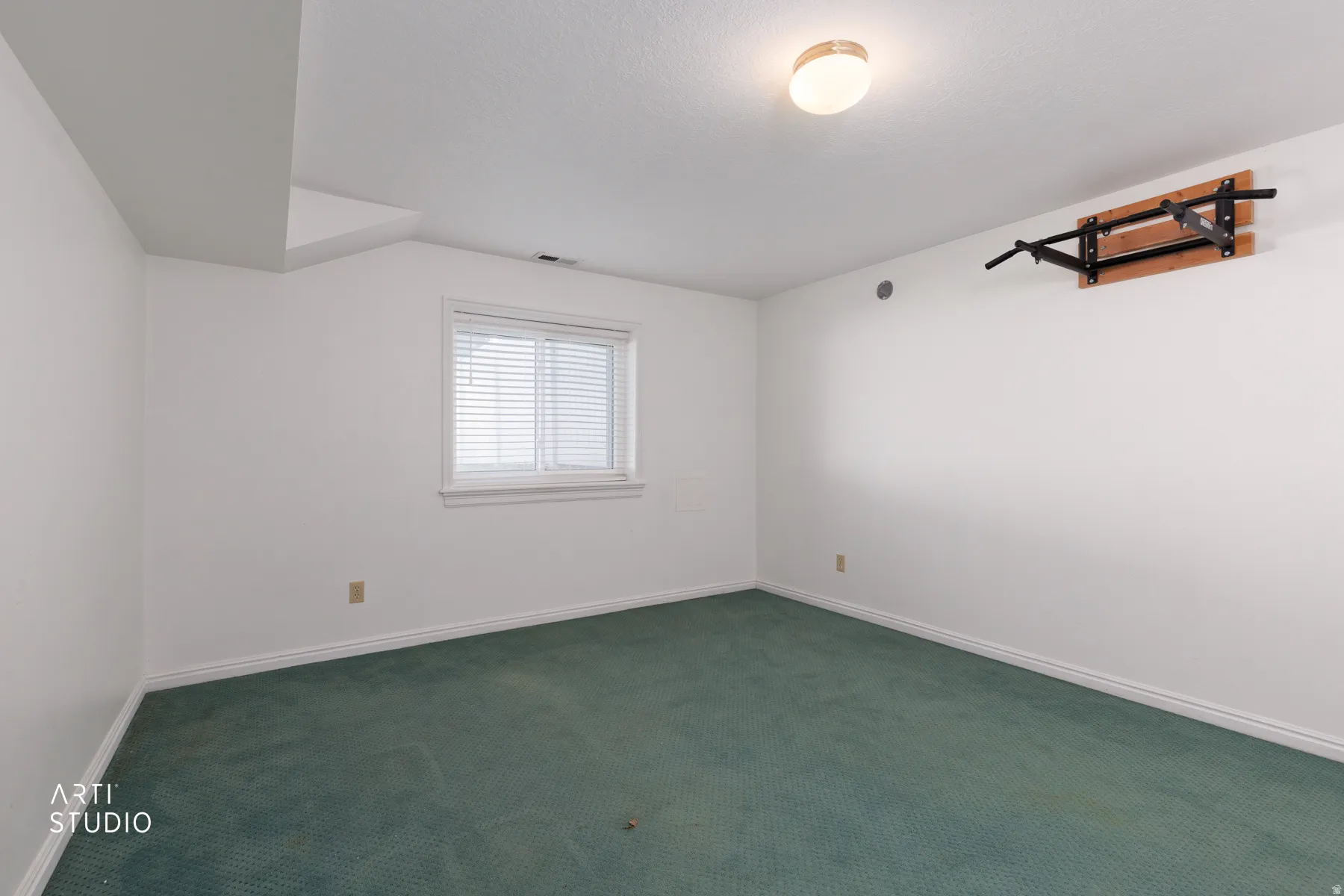 Recessed ceiling with an overhead light fixture, white walls, and a window with blinds
