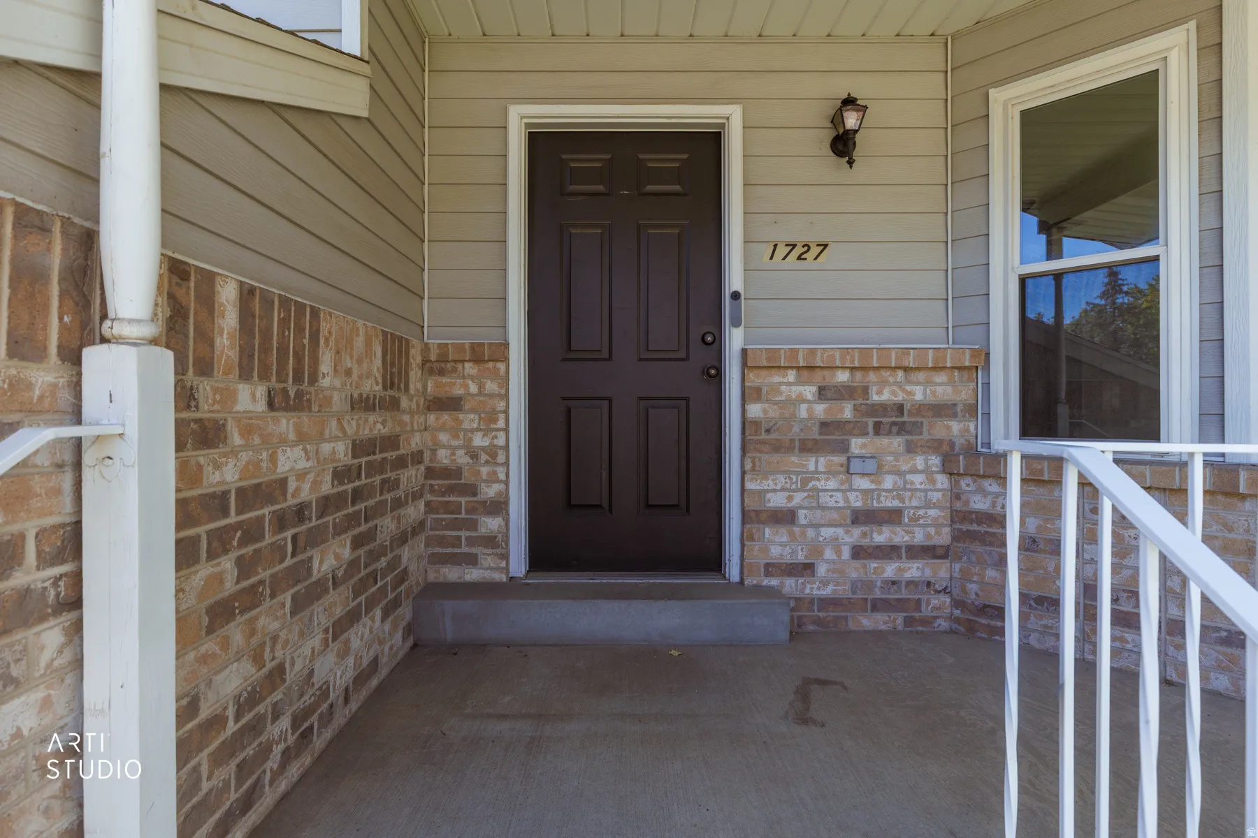 Inviting front entry featuring a paneled door, exterior wall lantern, and numerical address display