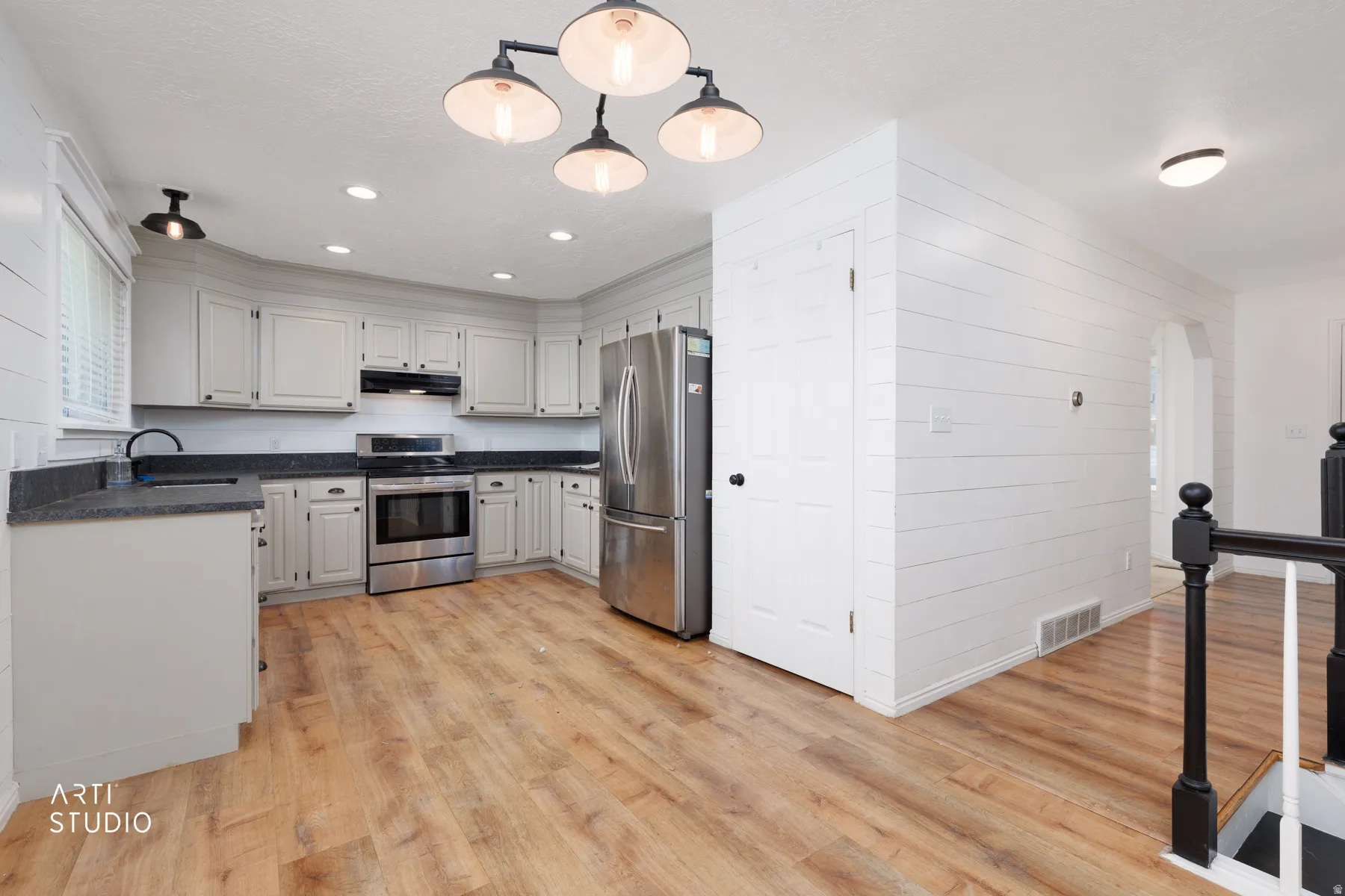 Kitchen featuring light wood-finish flooring, white cabinetry, dark countertops, and stainless steel appliances