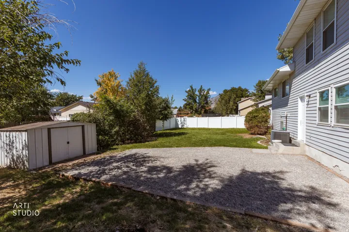 Expansive backyard featuring a gravel patio, manicured lawn, and mature trees