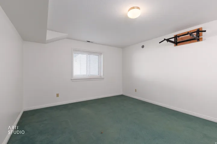 Recessed ceiling with an overhead light fixture, white walls, and a window with blinds