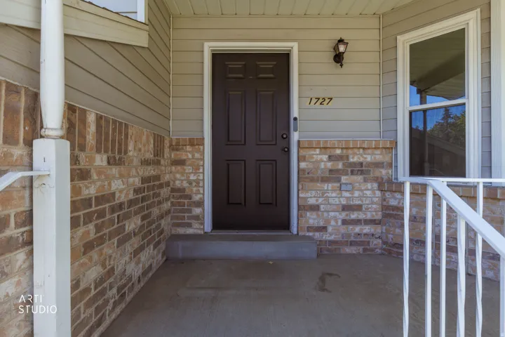 Inviting front entry featuring a paneled door, exterior wall lantern, and numerical address display