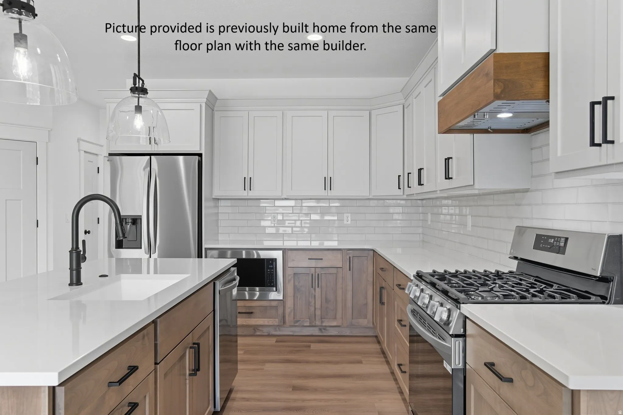 Kitchen featuring white upper cabinetry, wood-finish lower cabinetry, white subway tile backsplash, white countertops, and stainless steel appliances