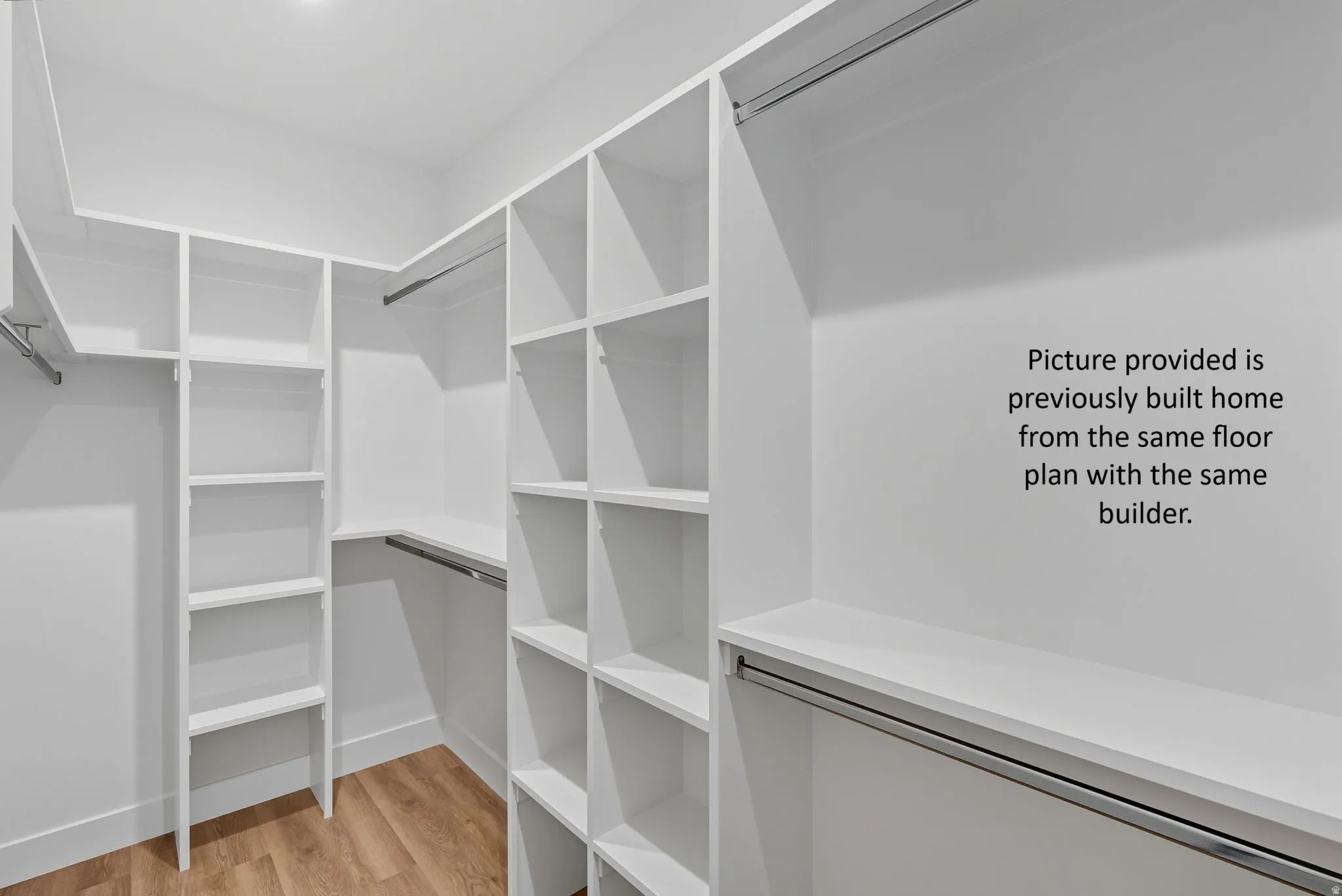 Custom built-in white shelving, wood-finish flooring, recessed ceiling light
