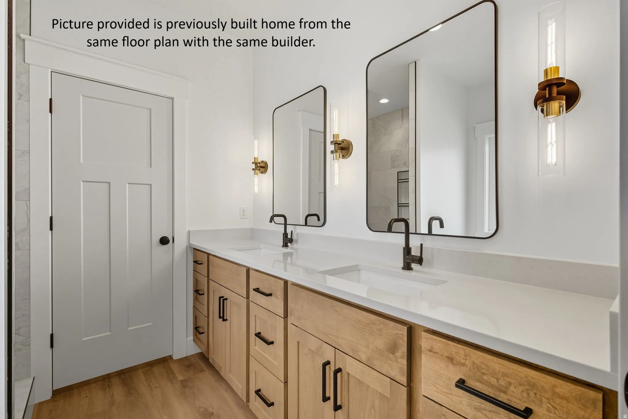Dual vanity with light wood-finish cabinetry, integrated sinks, and matte black fixtures