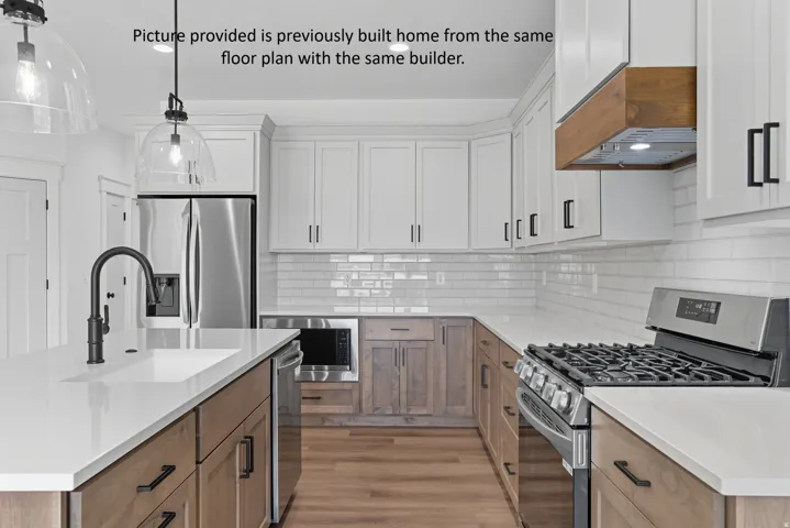 Kitchen featuring white upper cabinetry, wood-finish lower cabinetry, white subway tile backsplash, white countertops, and stainless steel appliances