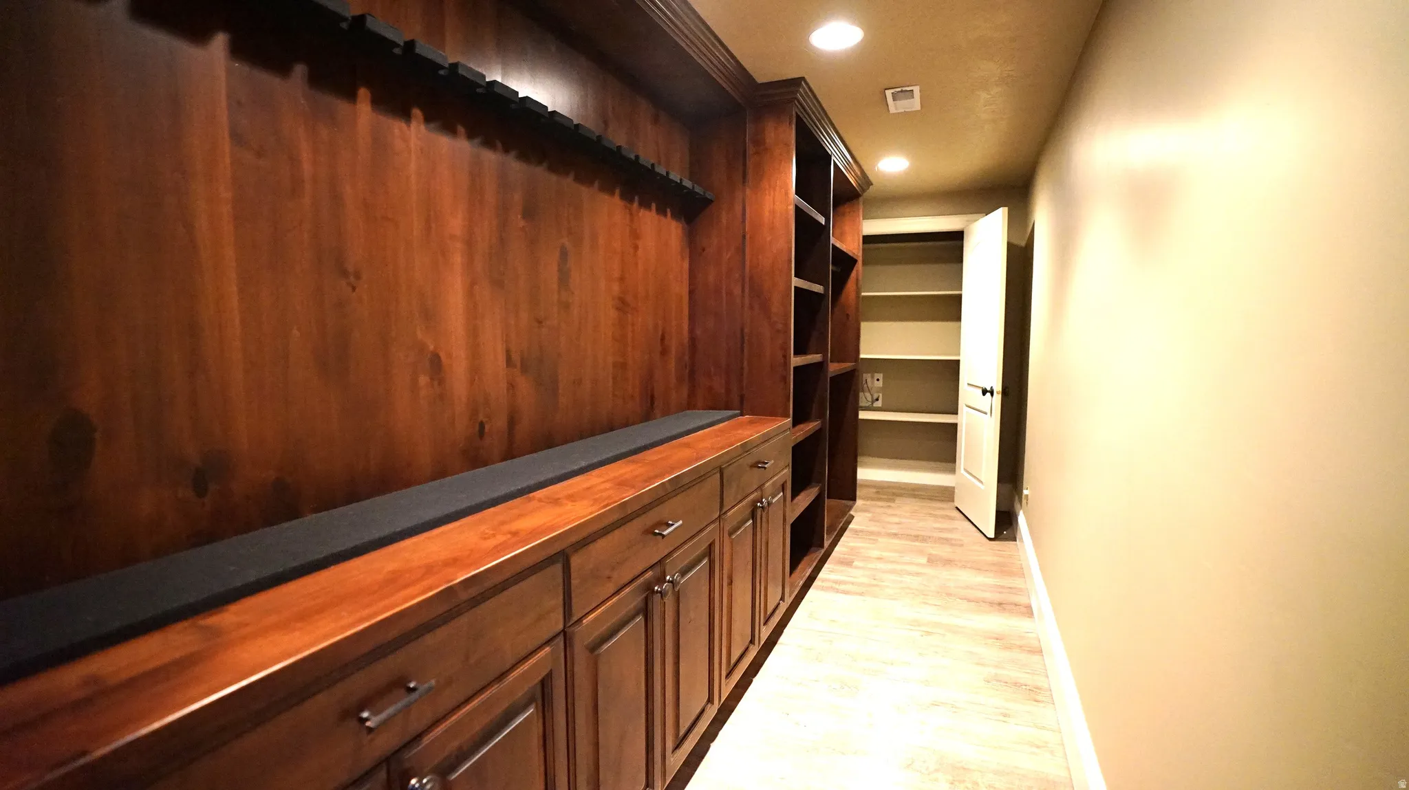 Built-in wood-finish cabinetry with drawers and storage, open shelving, recessed lighting, and wood-finish flooring