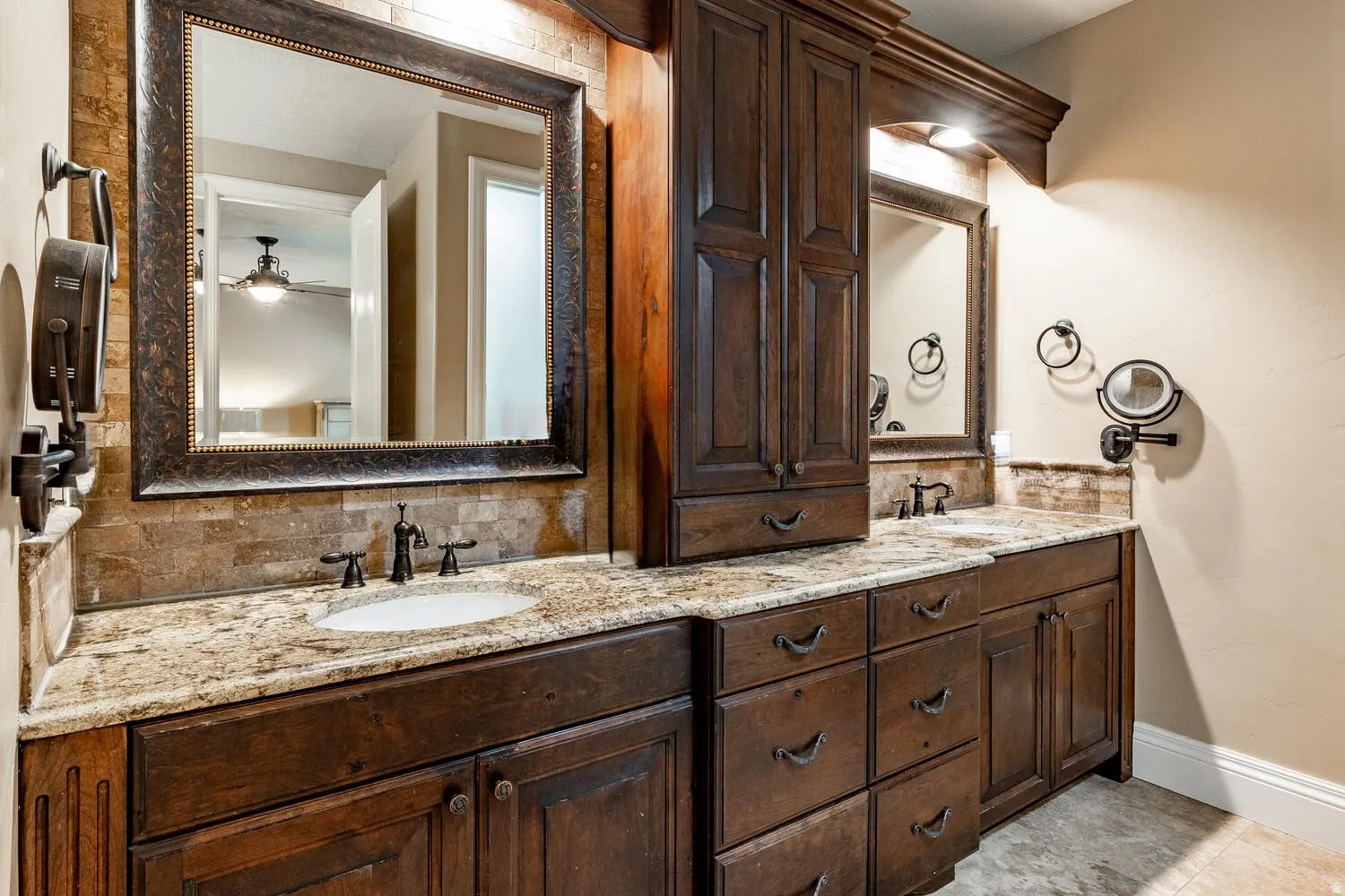 Dual vanities featuring undermount sinks, stone countertops, integrated cabinetry, and framed mirrors