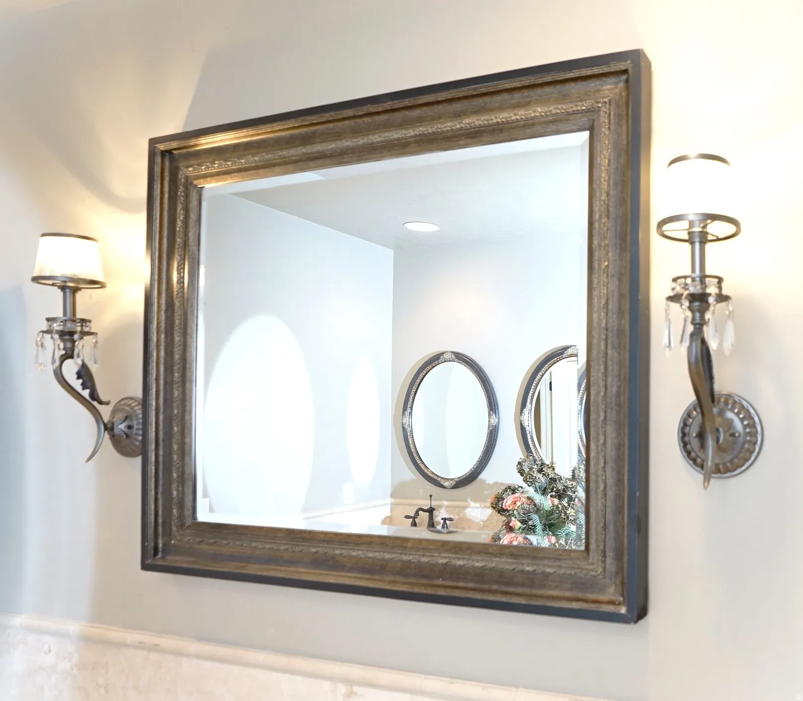 Rectangular framed mirror with ornate sconces featuring crystal accents