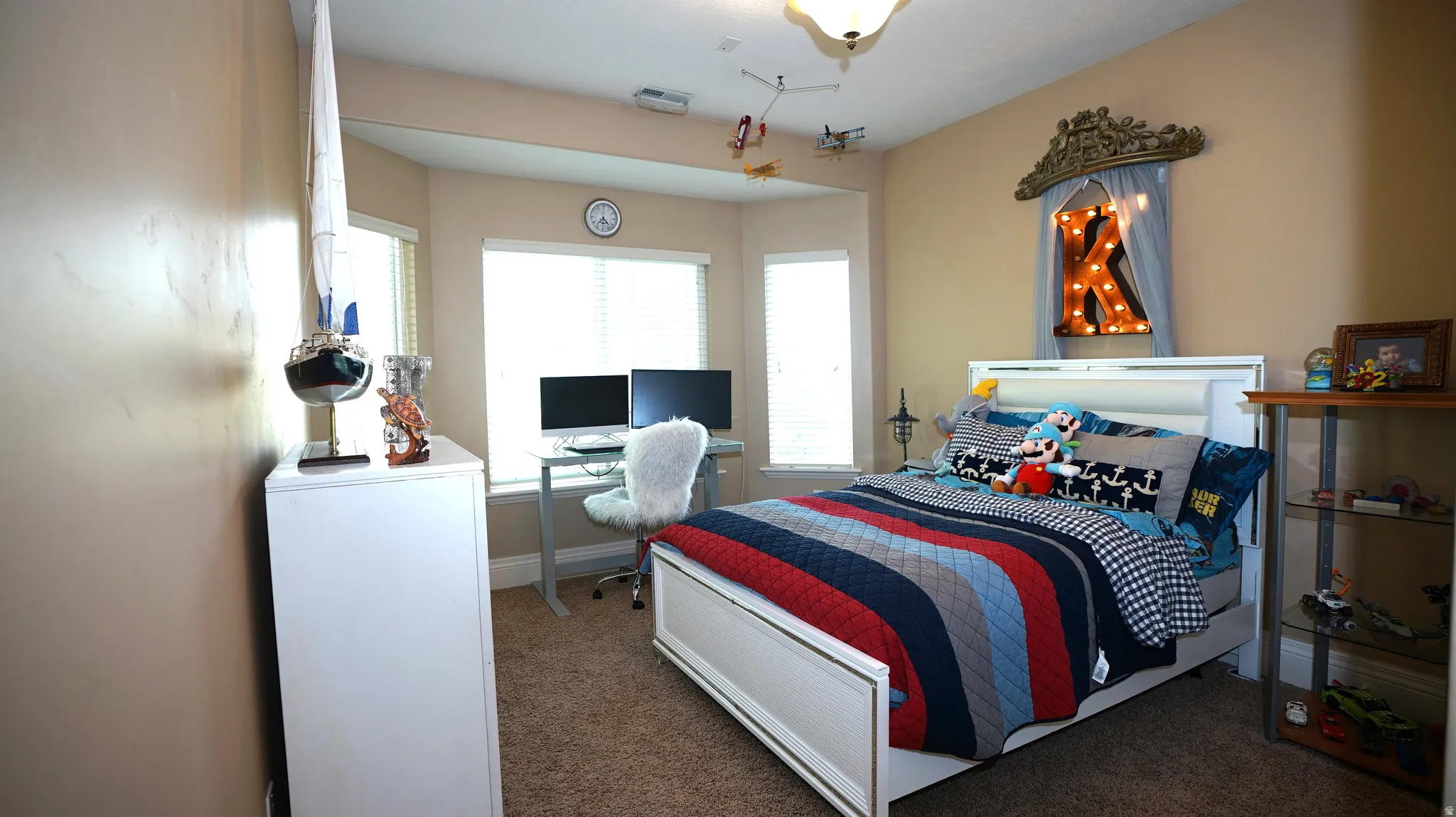 Recessed bay window, built-in shelving, carpet flooring, and a ceiling-mounted light fixture
