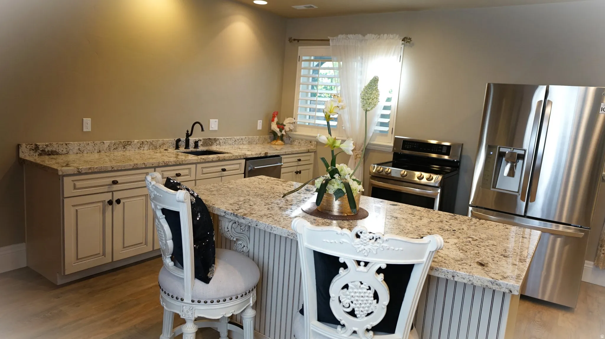 Kitchen featuring granite countertops, built-in cabinetry, stainless steel appliances, and wood-finish flooring