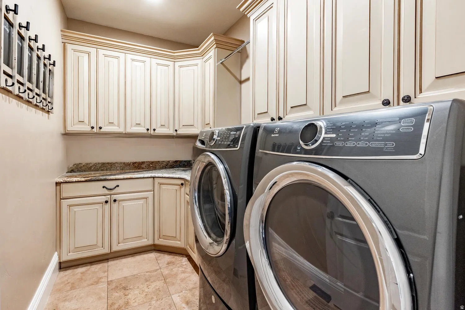 Built-in cabinetry with crown molding, stone-finish countertops, tiled flooring, and front-loading appliances