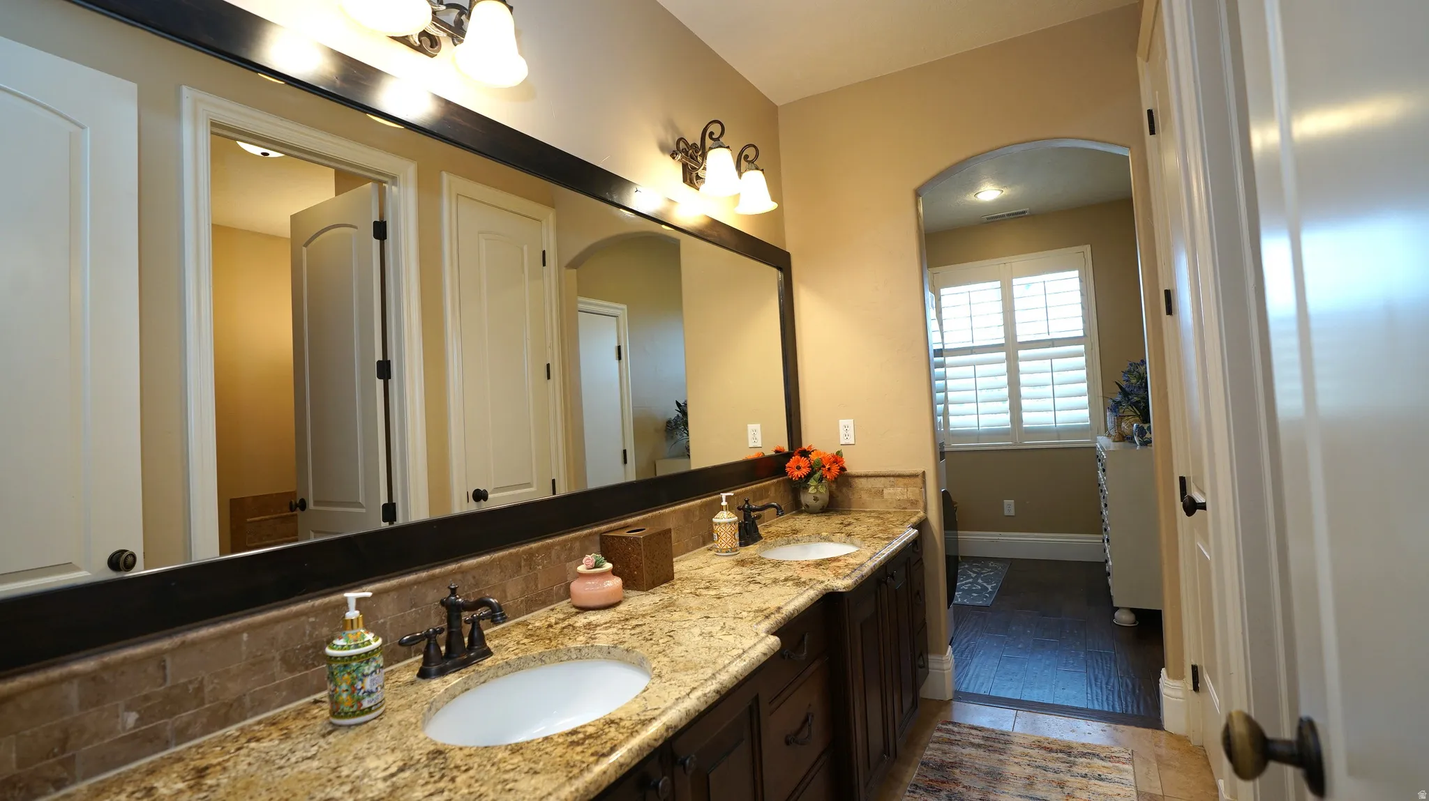 Dual vanity with undermount sinks, rich wood-finish cabinetry, and stone countertops
