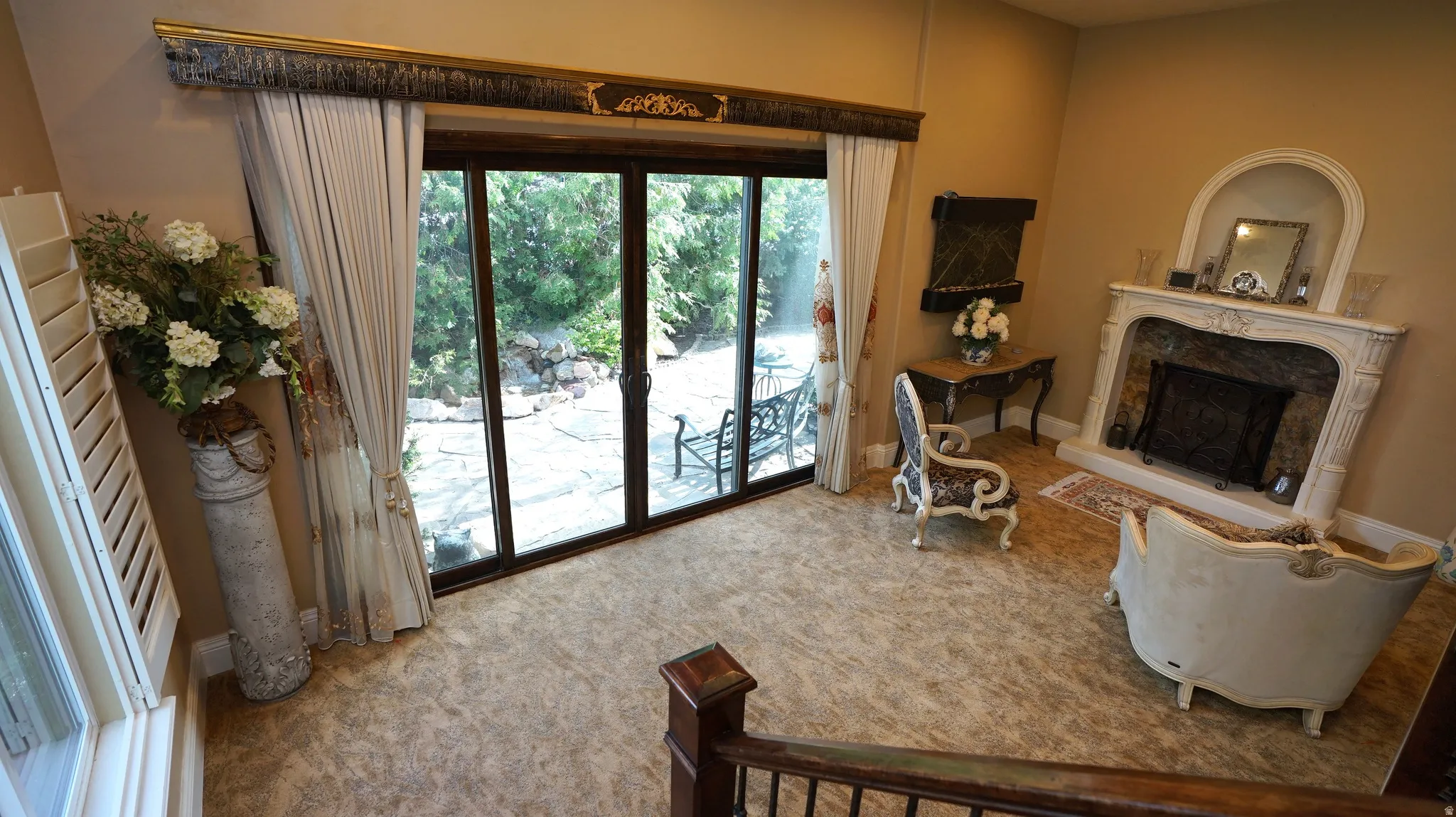 Arched fireplace with decorative mantel, glass slider doors, and shuttered window