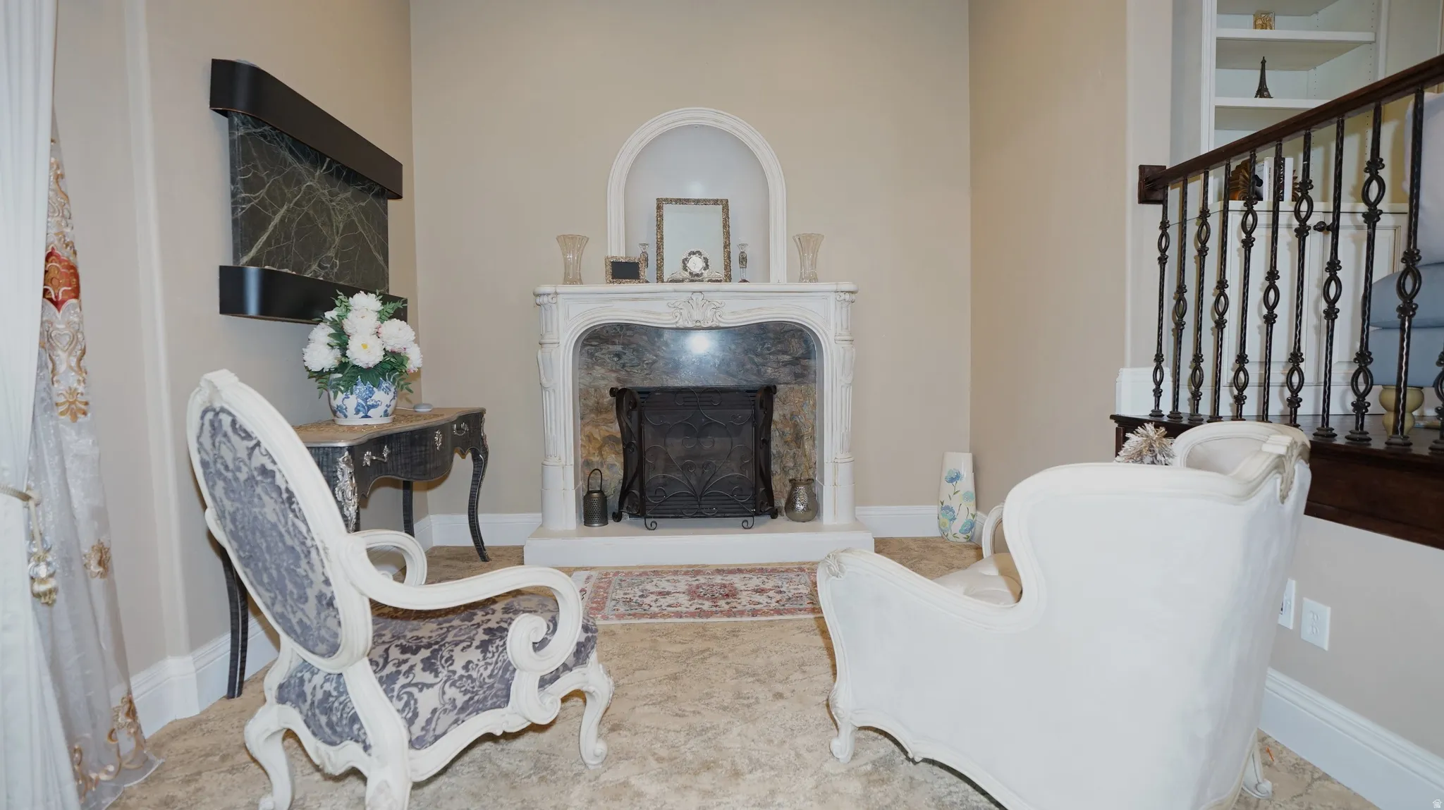 Ornate fireplace with a decorative mantel and hearth, built-in wall niche, wrought iron staircase railing, and built-in shelving