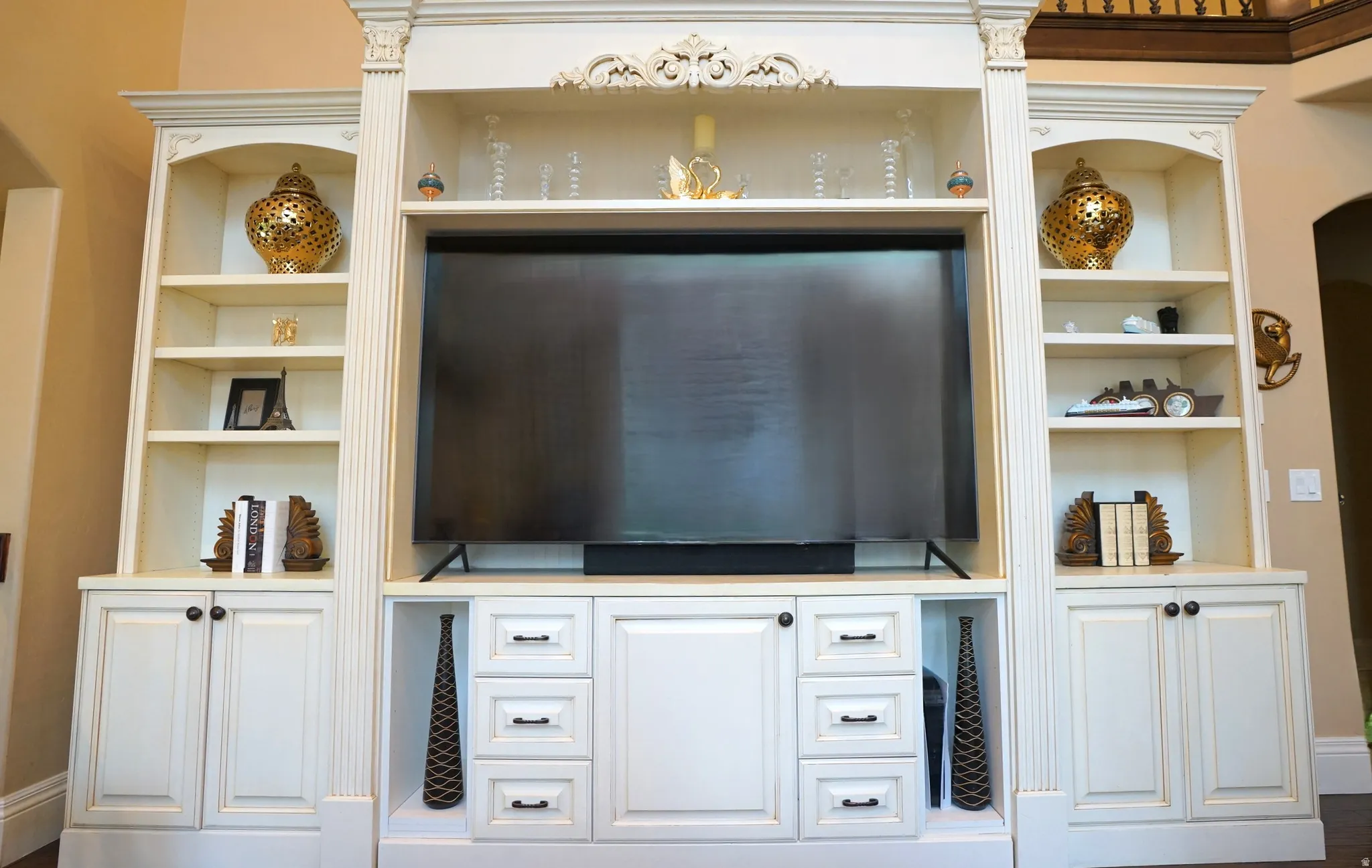 Built-in entertainment center featuring extensive shelving, integrated cabinetry, decorative molding, and fluted columns