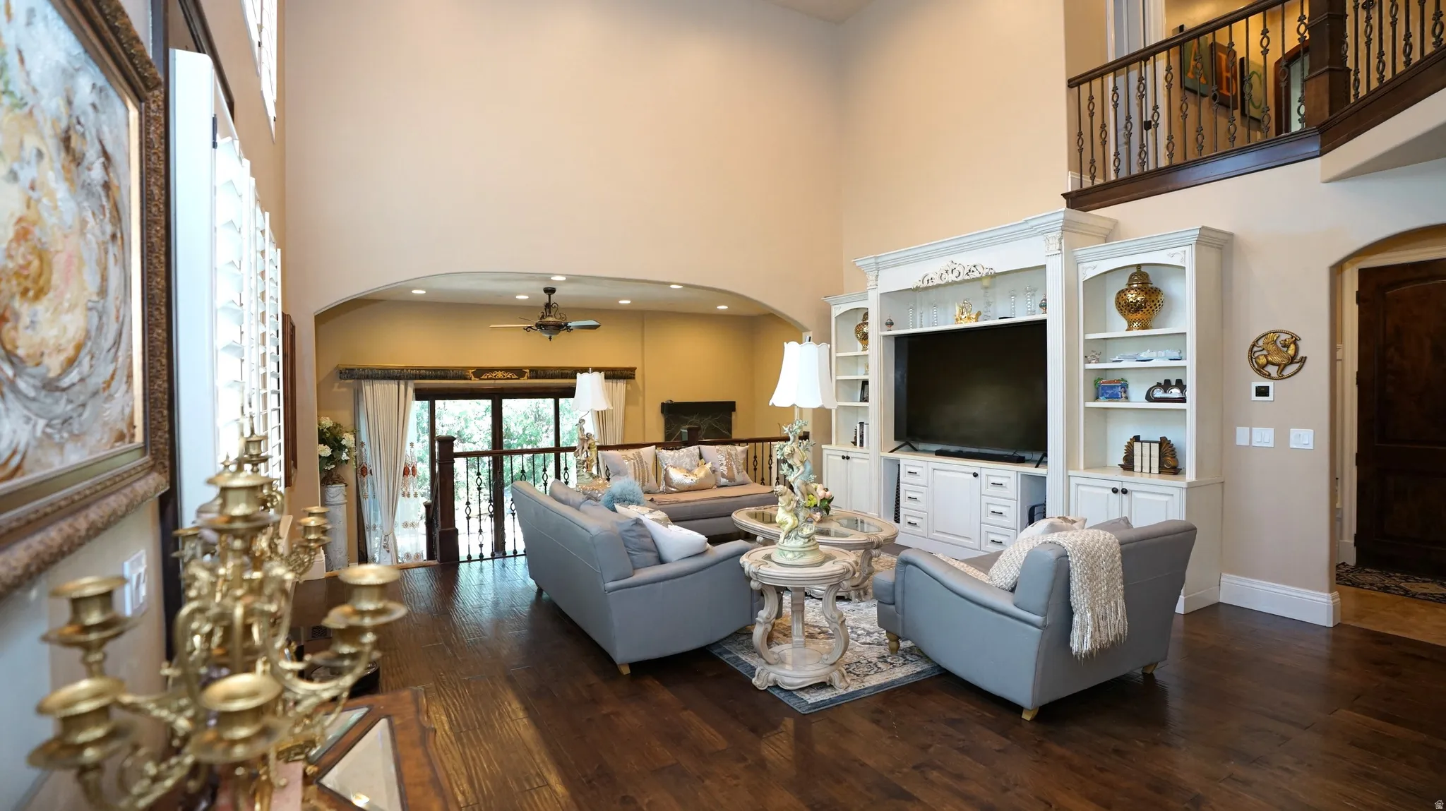 Expansive living area featuring soaring ceilings, dark wood-finish flooring, and a built-in entertainment center with integrated shelving