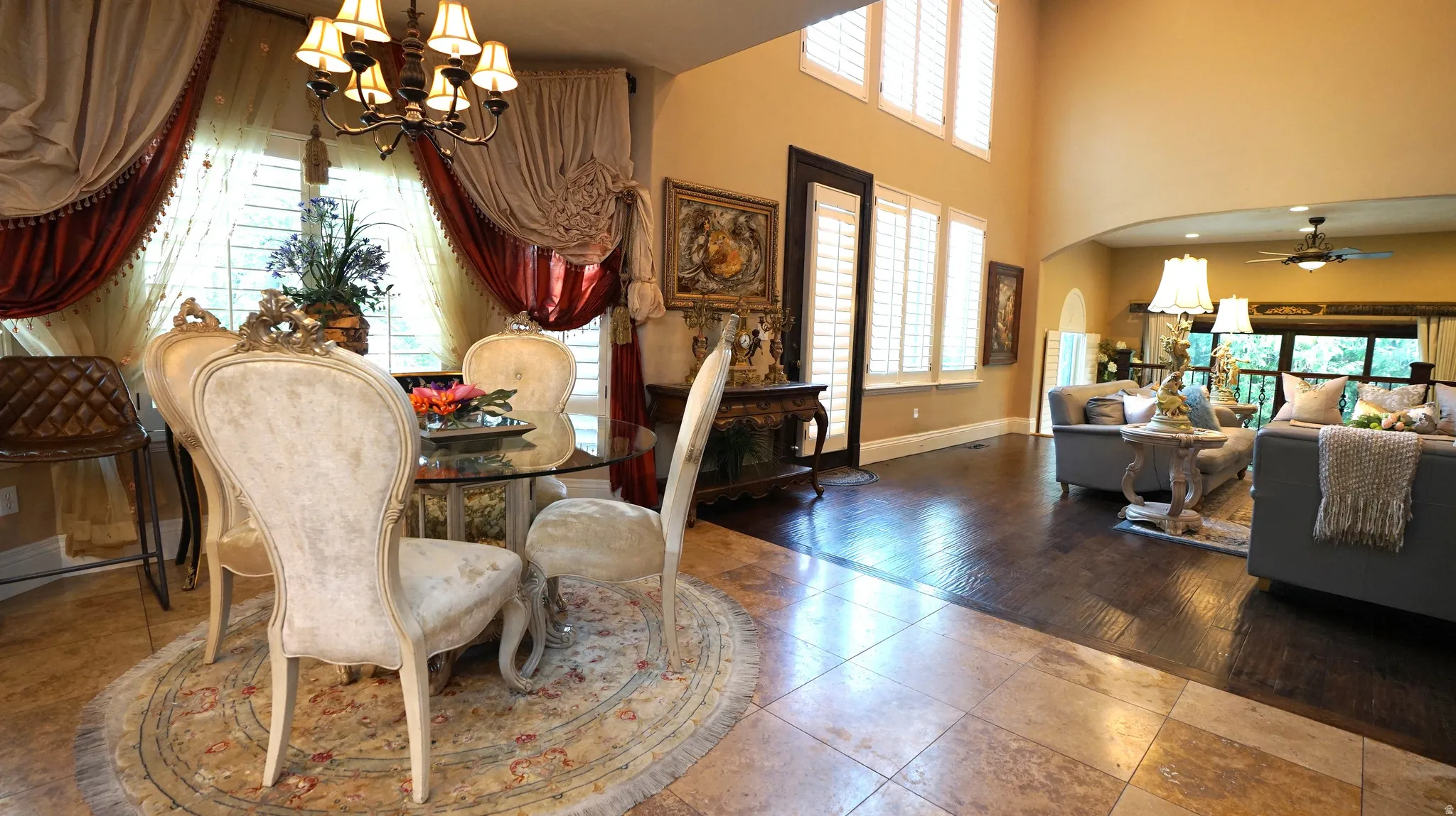 Two-story living area with arched entry, hardwood flooring, and abundant natural light