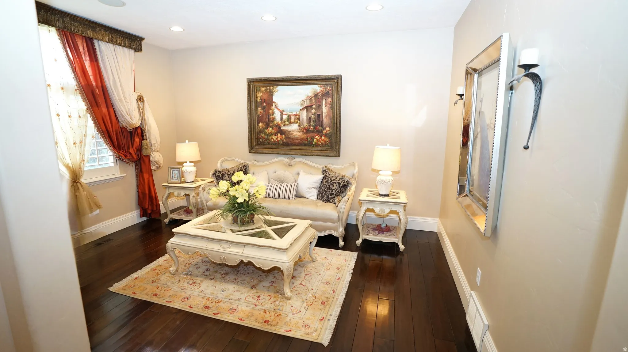 Hardwood flooring throughout, recessed ceiling lighting, wall-mounted sconce lighting, and a large window with custom window treatments
