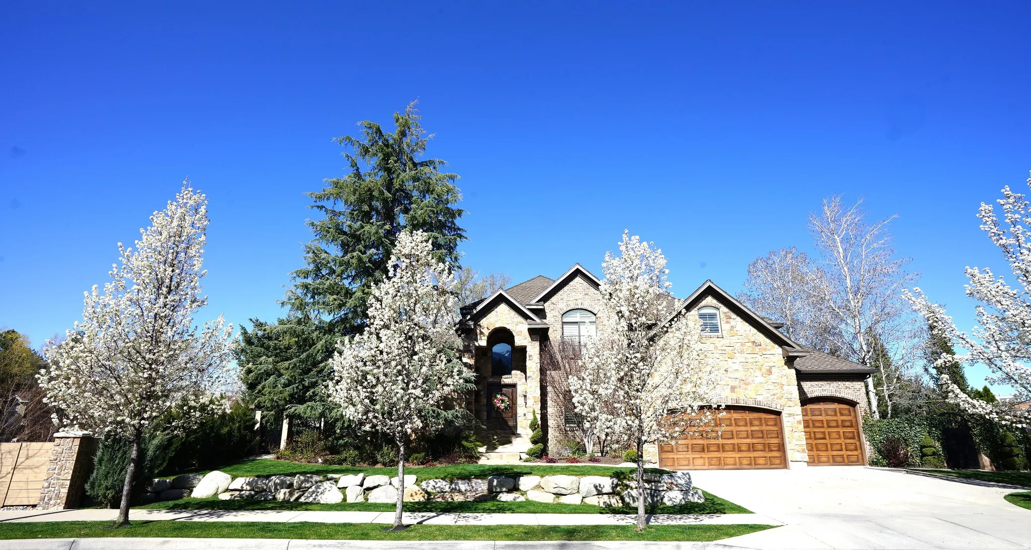 Stone exterior residence with an arched entry, multiple gables, and two wood-finish garage doors