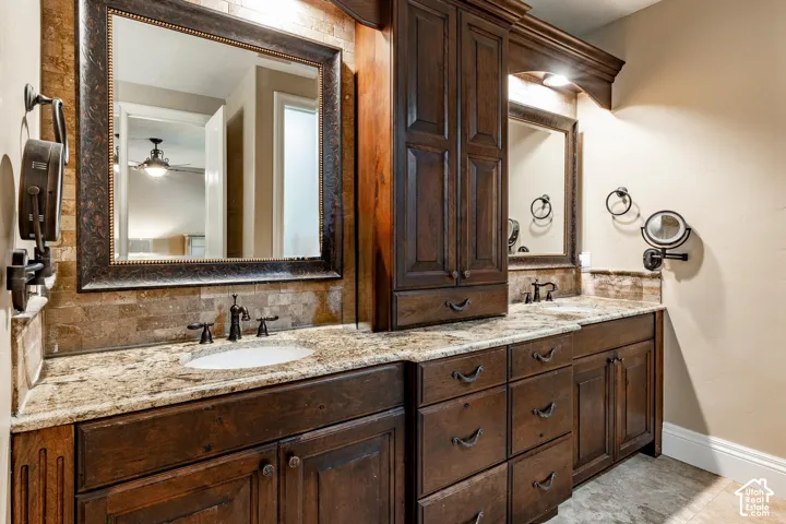 Dual vanities featuring undermount sinks, stone countertops, integrated cabinetry, and framed mirrors