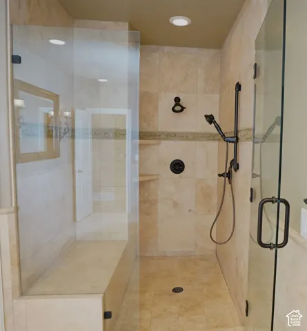 Glass-enclosed shower with a built-in bench, natural stone tile, and oil-rubbed bronze fixtures