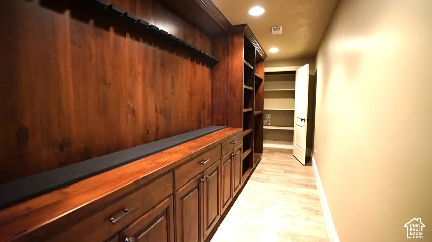 Built-in wood-finish cabinetry with drawers and storage, open shelving, recessed lighting, and wood-finish flooring