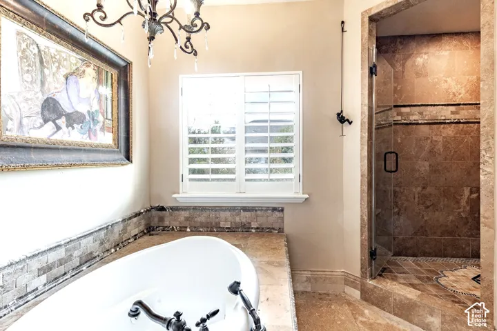 Freestanding bathtub with dark bronze fixtures, adjacent to a walk-in shower with glass enclosure