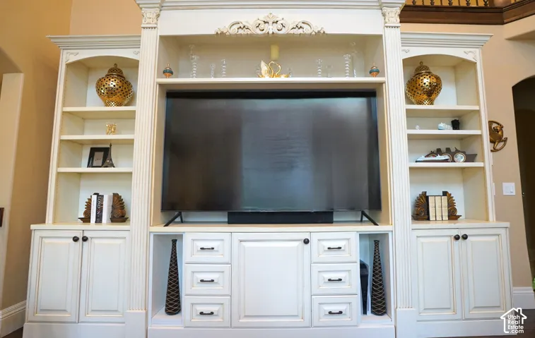 Built-in entertainment center featuring extensive shelving, integrated cabinetry, decorative molding, and fluted columns